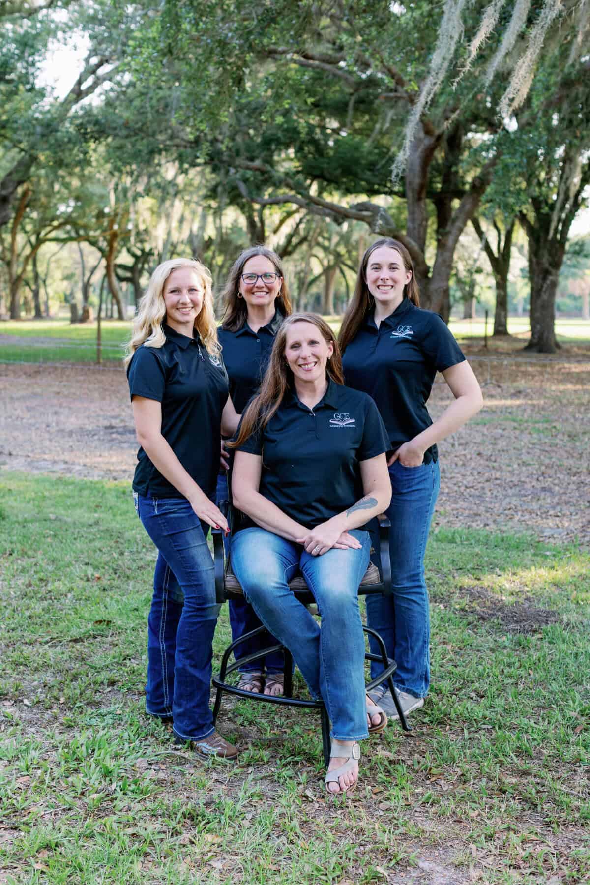 A group of four women outdoors, smiling, representing a classical Christian homeschool community.