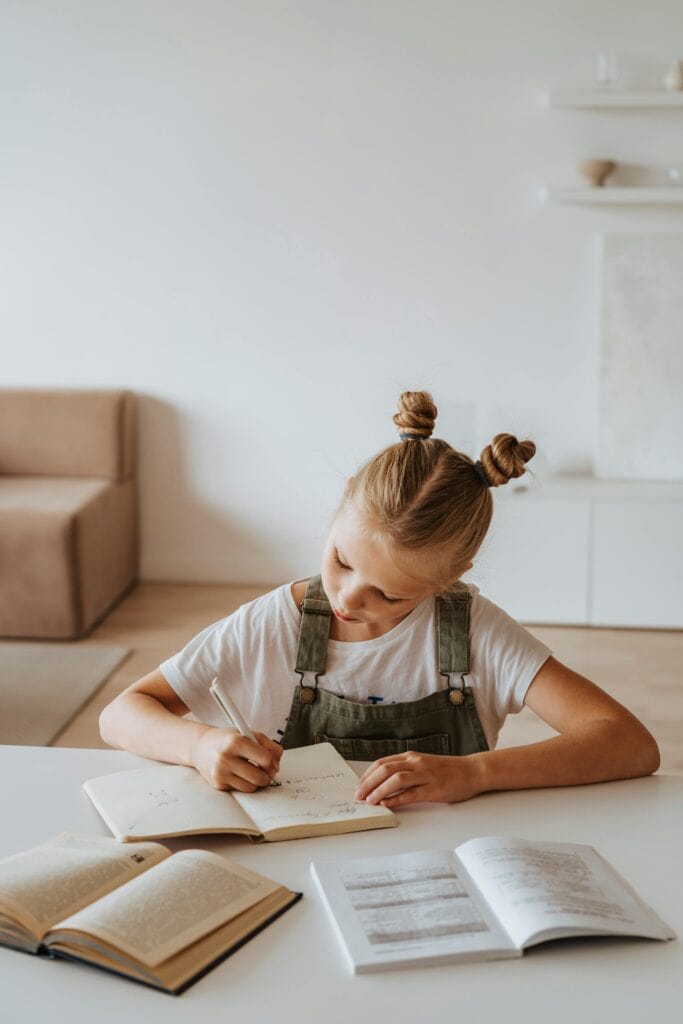 A young girl studying with books, engaging in classical education stages at home.