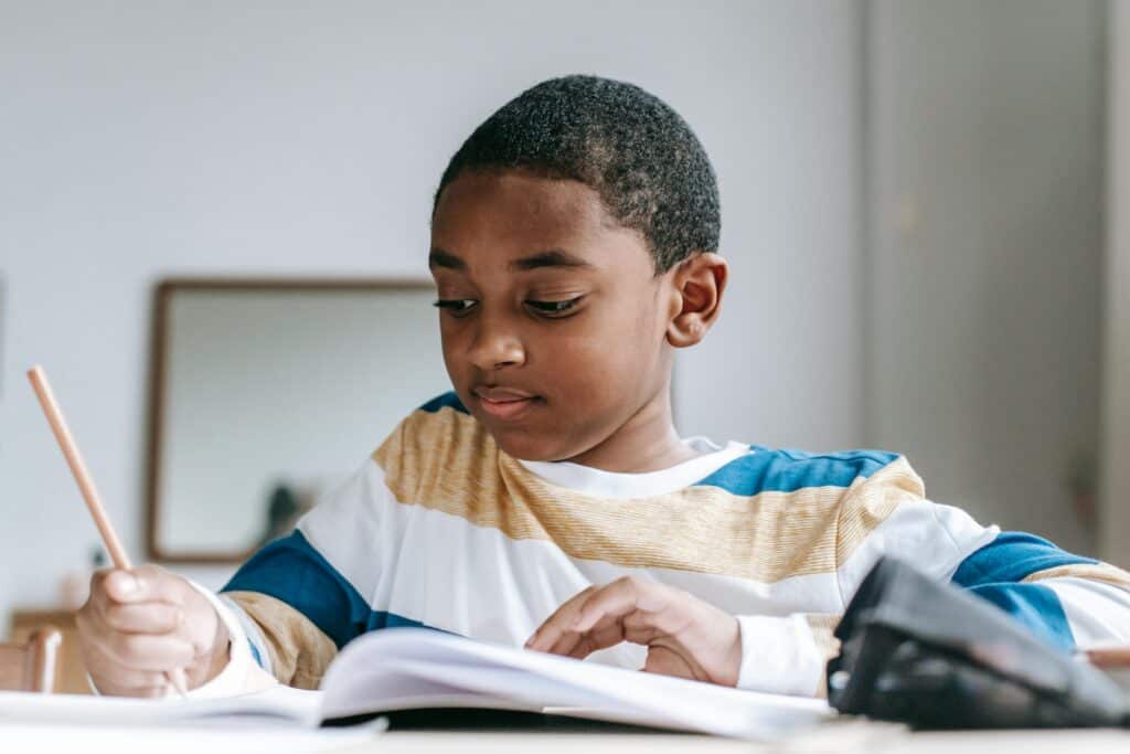 Young student engaged in learning at home, practicing writing and reading in a homeschool setting.